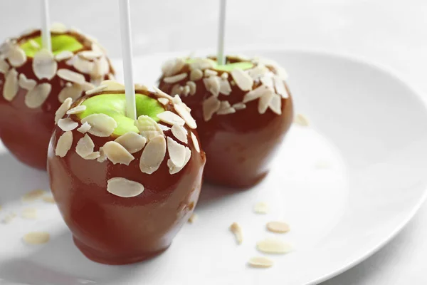 Assiette avec de délicieuses pommes au caramel sur fond clair — Photo