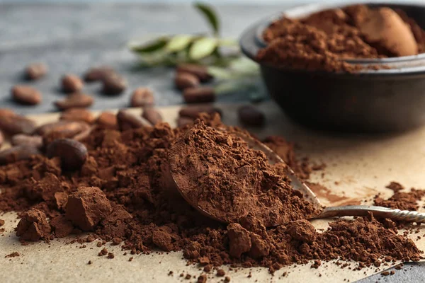 Cuchara y pila de cacao en polvo sobre la mesa —  Fotos de Stock