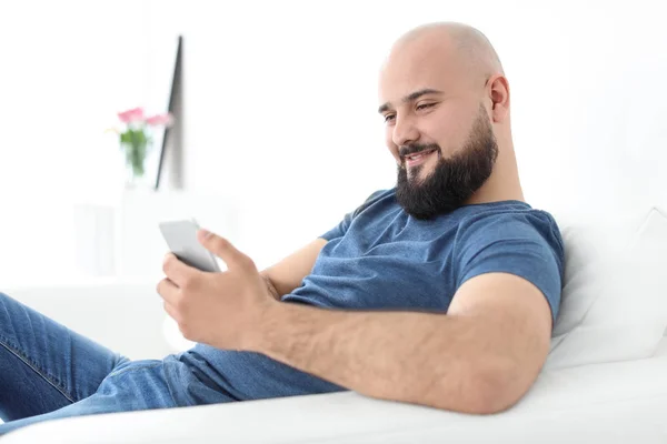 Porträt eines jungen Mannes mit Handy auf dem Sofa — Stockfoto