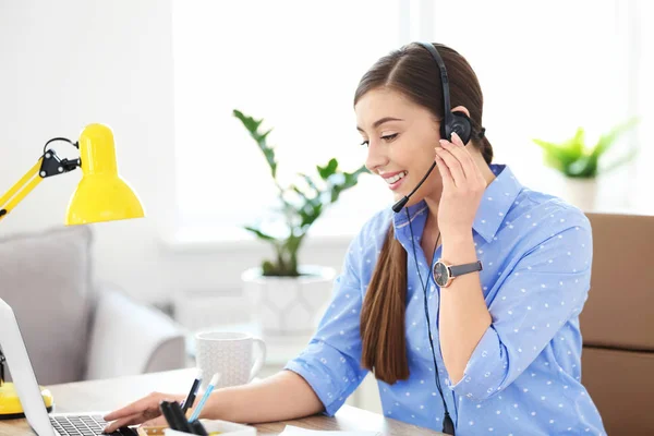 Junge Frau telefoniert am Arbeitsplatz über Headset — Stockfoto