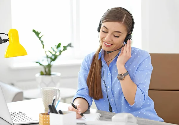 Молода жінка говорить по телефону через гарнітуру на робочому місці — стокове фото