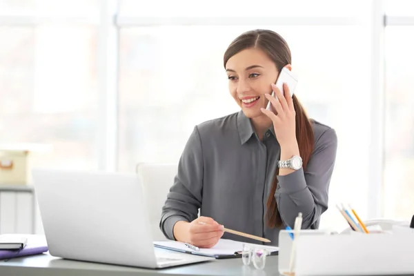Mujer joven hablando por teléfono en el lugar de trabajo —  Fotos de Stock