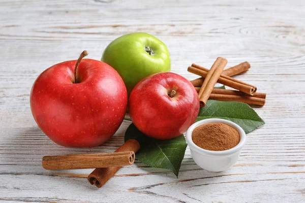 Verse appels met kaneelstokjes en poeder op houten tafel — Stockfoto