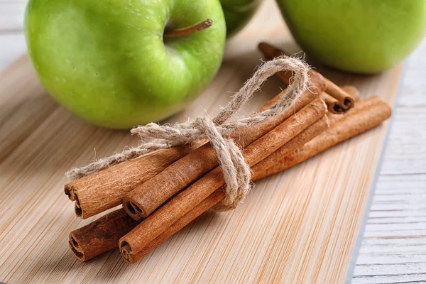 Verse appel- en kaneelstokjes op houten bord — Stockfoto