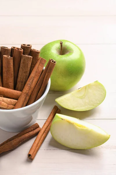 Manzanas frescas y palitos de canela en la mesa — Foto de Stock
