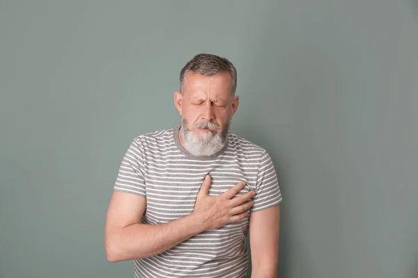 Hombre maduro teniendo un ataque al corazón en el fondo de color — Foto de Stock