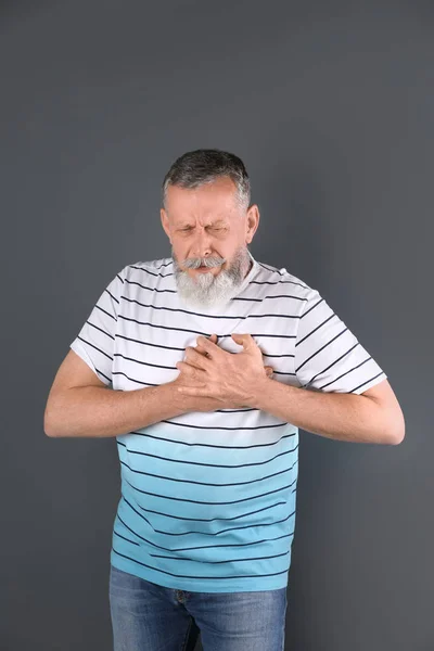 Mature man having heart attack on gray background — Stock Photo, Image