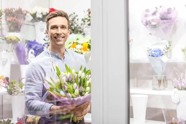 Kwiaciarnia mężczyzna trzyma bukiet kwiatów w miejscu pracy — Zdjęcie stockowe