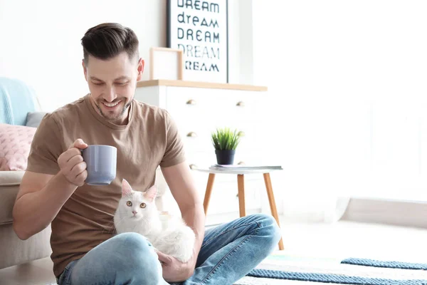 Junger Mann mit süßer Katze sitzt zu Hause auf dem Boden — Stockfoto