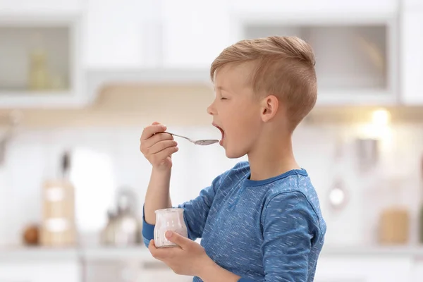 Liten pojke med yoghurt på suddig bakgrund — Stockfoto