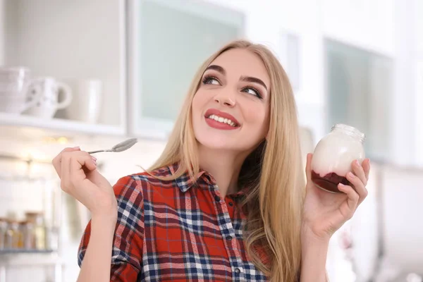 Молода жінка з йогуртом на кухні — стокове фото