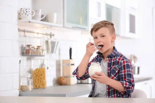 Little boy with yogurt in kitchen — Stock Photo, Image