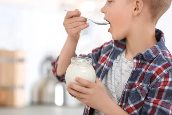 Liten pojke med yoghurt på suddig bakgrund, närbild — Stockfoto