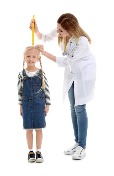Médico que mede a altura da menina no fundo branco — Fotografia de Stock