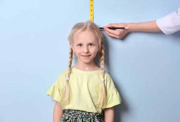 Médico medir a altura da menina no fundo de luz — Fotografia de Stock