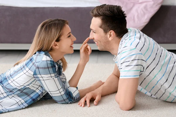 Encantador jovem casal deitado no tapete acolhedor em casa — Fotografia de Stock