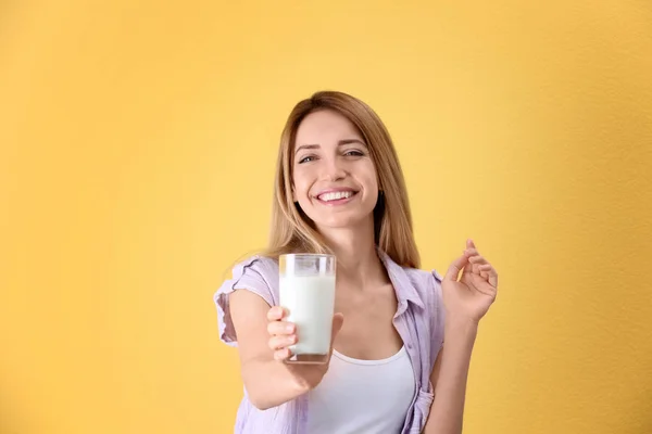 Mooie jonge vrouw drinken melk op kleur achtergrond — Stockfoto