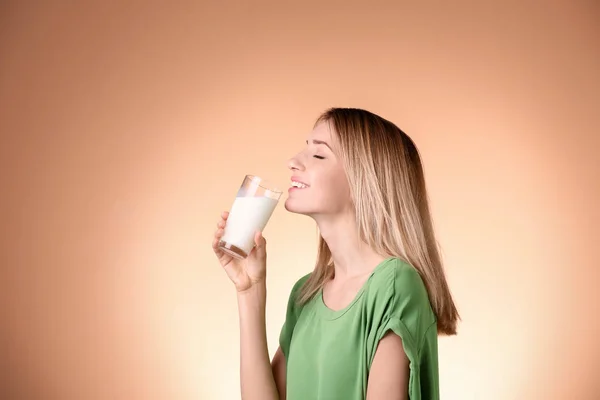 Bella giovane donna che beve latte su sfondo di colore — Foto Stock