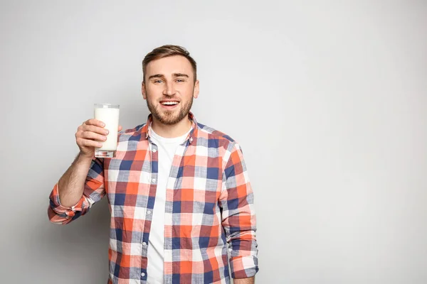 Young man with glass of tasty milk on light background — Stock Photo, Image