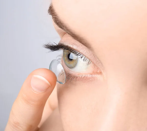 Молодая женщина кладет контактные линзы в глаз, крупным планом — стоковое фото