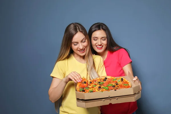 Jeunes femmes attrayantes avec de délicieuses pizzas sur fond de couleur — Photo