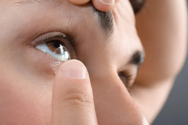 Молодой человек вставляет контактные линзы в глаз, крупным планом — стоковое фото