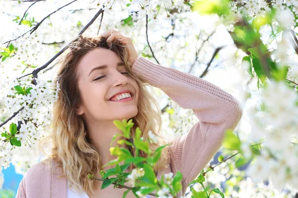 Atractiva joven posando cerca de un árbol en flor en el soleado día de primavera —  Fotos de Stock