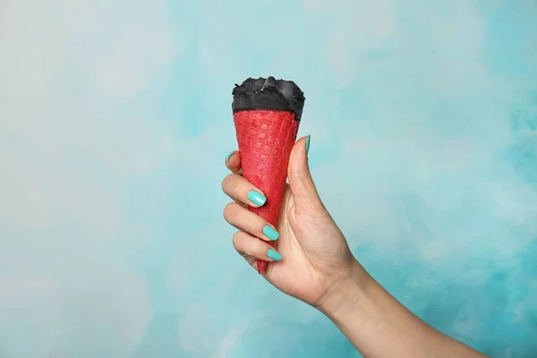 Mujer sosteniendo delicioso helado sobre fondo de color. Céntrate en la mano — Foto de Stock