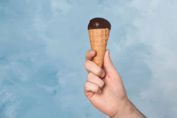 Uomo in possesso di gelato gustoso su sfondo di colore. Focus a portata di mano — Foto Stock