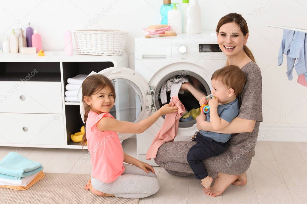 Housewife with little children doing laundry at home