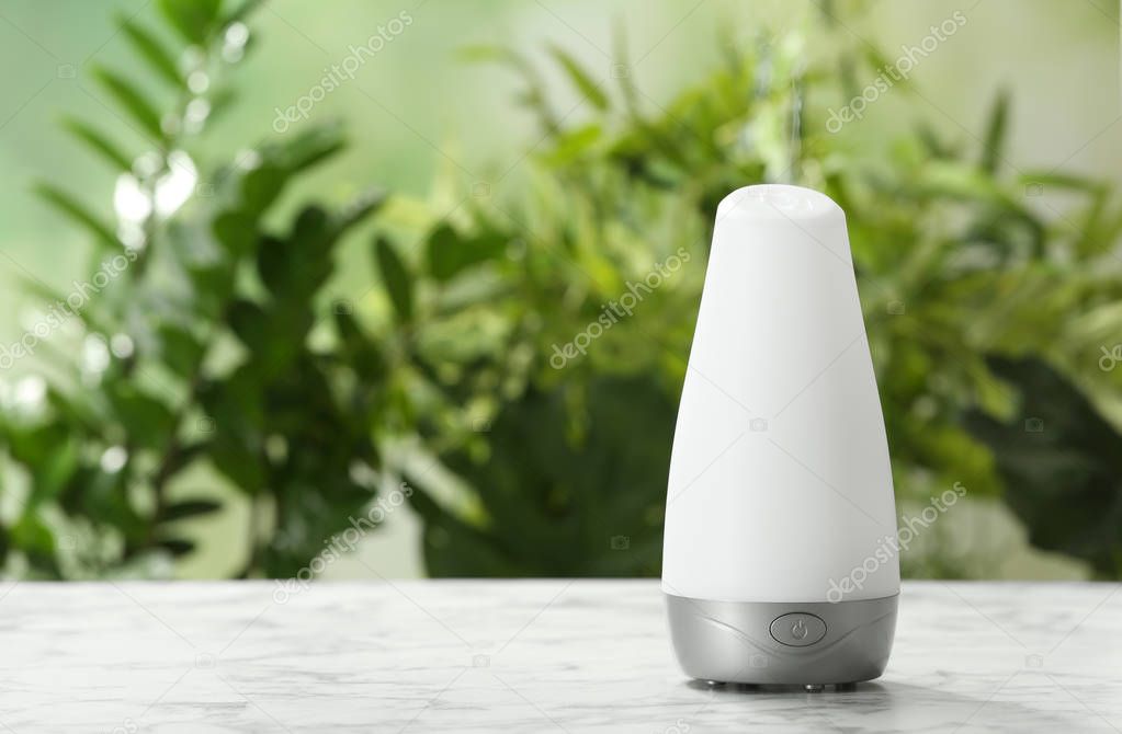 Aroma oil diffuser on table against blurred background. Air freshener