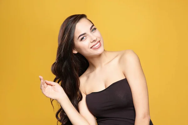 Portret van mooie model met prachtig krullend haar op kleur achtergrond — Stockfoto