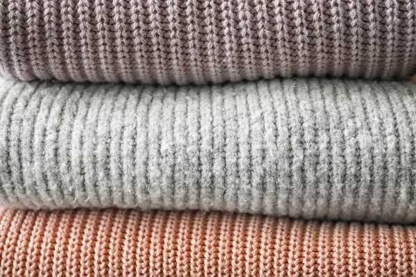 Stack of warm knitted clothes as background