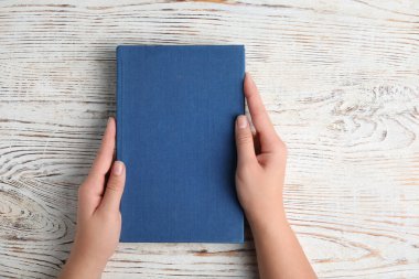 Beyaz ahşap arka plan, üst manzara hakkında kitap tutan kadın.