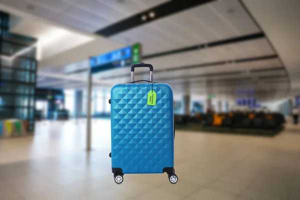 Blauer Koffer mit Reiseversicherungsetikett im Flughafenterminal — Stockfoto