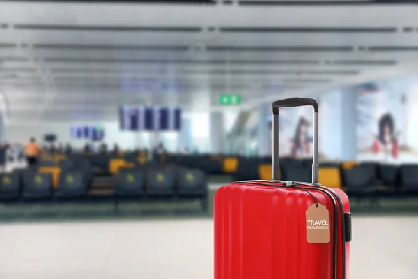 공항 터미널에 여행 보험 회사가 있는 빨간 여행 가방 — 스톡 사진