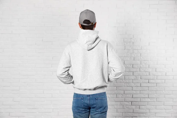 Junger Mann im Pullover an der Ziegelwand. Mock up für Design — Stockfoto