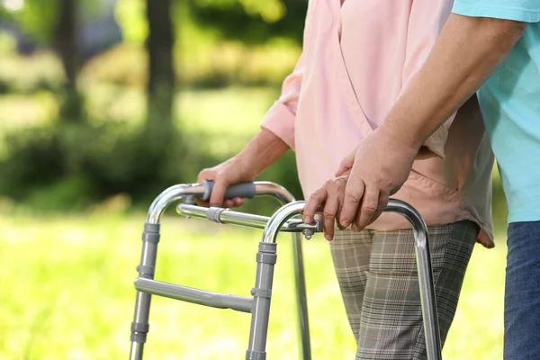 Äldre man hjälpa sin fru med promenad ram utomhus, närbild — Stockfoto