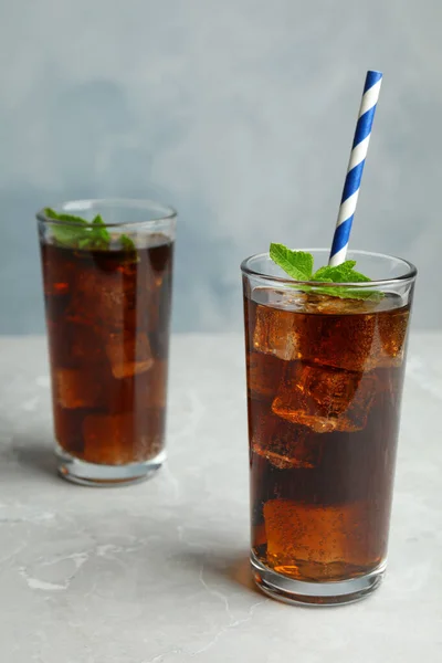 Refrescantes bebidas gaseosas con paja sobre una mesa gris sobre fondo azul — Foto de Stock