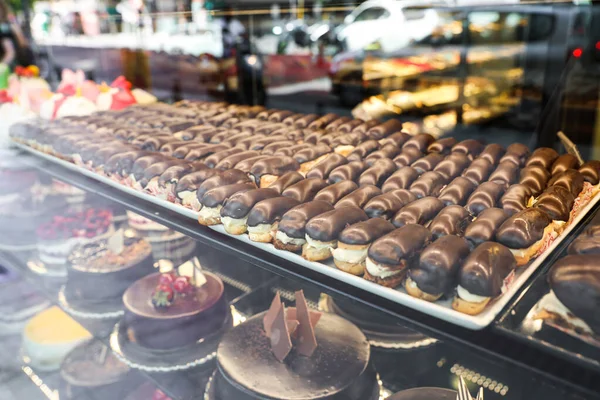 Diferentes deliciosos pasteles en exhibición en la cafetería, vista a través de la ventana — Foto de Stock