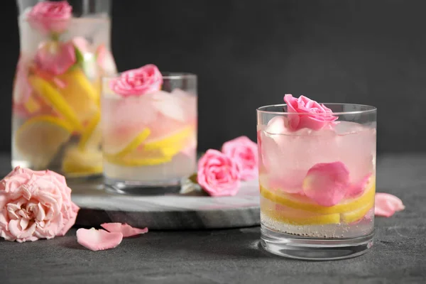 Köstliches Erfrischungsgetränk mit Zitrone und Rosen auf grauem Tisch — Stockfoto