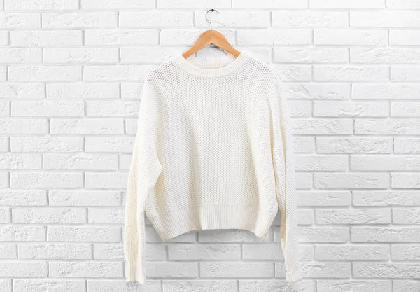 Hanger with stylish sweater on brick wall — Stock Photo, Image