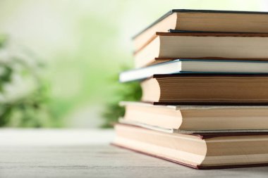 Ahşap masadaki bir yığın ciltli kitap bulanık arka plana karşı, yakın plan. Metin için boşluk