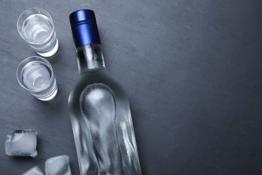 Bir şişe votka, buz küpleri ve siyah masada shot bardakları. Metin için boşluk