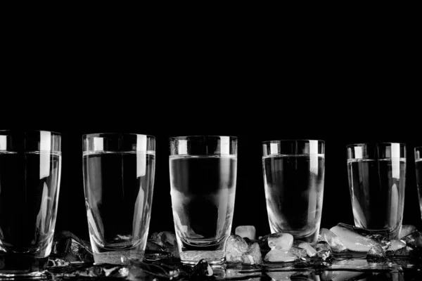 Vodka dans des verres de tir et de la glace sur fond noir — Photo