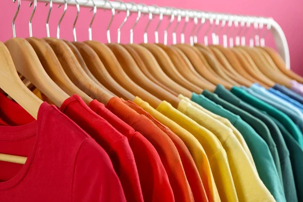 Cremalheira com roupas brilhantes no fundo rosa. Cores arco-íris — Fotografia de Stock