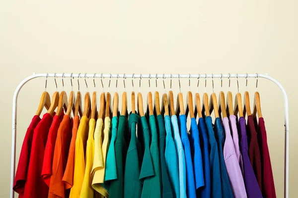 Rack met heldere kleren op lichte achtergrond. Regenboog kleuren — Stockfoto