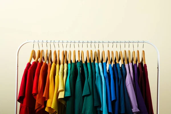 Rack met heldere kleren op lichte achtergrond. Regenboog kleuren — Stockfoto