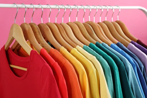 Bastidor con ropa brillante sobre fondo rosa. Colores del arco iris —  Fotos de Stock