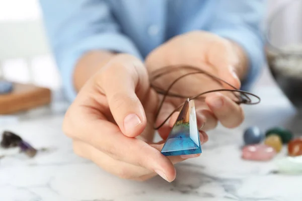 Woman holding handmade gemstone amulet at table, closeup — Stock Photo, Image